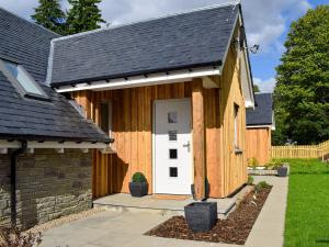 ein Holzhaus mit einer weißen Tür und einem Zaun in der Unterkunft Kenmore Lodge in Kenmore
