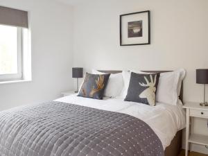 a white bedroom with a bed with two deer pillows at Kenmore Lodge in Kenmore