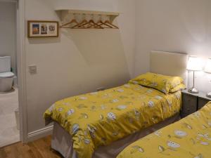a bedroom with two beds with yellow sheets at Blyth Green Stable in Long Stratton