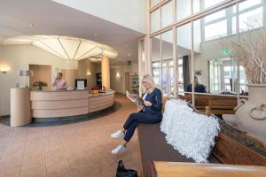 a woman sitting on a bench in a lobby at Thiesmann´s Hotel & Restaurant in Mülheim an der Ruhr