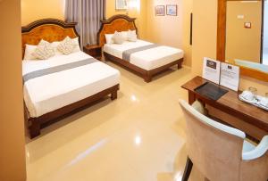 圣何塞RedDoorz Plus @ Hotel Platinum Occidental Mindoro的有两张床、一张桌子和一张书桌的房间