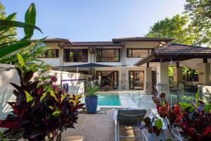 a house with a swimming pool in front of it at NYARU Villa Port Douglas, QLD in Port Douglas