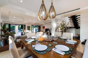 a dining room and living room with a table and chairs at NYARU Villa Port Douglas, QLD in Port Douglas