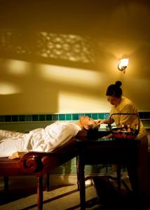 Eine Frau, die neben einem Mann im Bett steht. in der Unterkunft The Majestic Malacca Hotel - Small Luxury Hotels of the World in Malakka