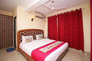 1 dormitorio con 1 cama grande y cortinas rojas en Sea Breeze Beach Resort Murud, en Murud