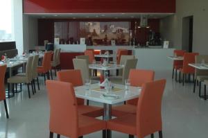 a restaurant with white tables and orange chairs at Keys Select by Lemon Tree Hotels, Ludhiana in Ludhiana