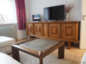 a living room with a wooden entertainment center with a flat screen tv at Ferienwohnung Schlossblick in Amtzell