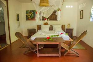 - une chambre avec un lit, une table et des chaises dans l'établissement Analatsara Eco Lodge, sur l'île aux Nattes