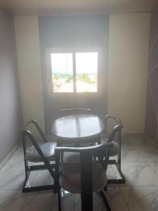 a table and chair in a room with a window at Impeccable Apartment in Abidjan Cote D'avoire in Abidjan