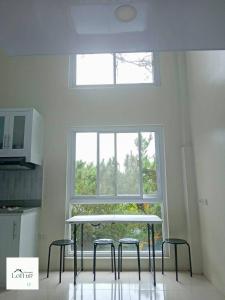 een keuken met een tafel en drie krukken voor een raam bij Minimalist Loft 107 in Baguio
