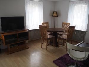 sala de estar con mesa, sillas y TV en Ferienwohnung am Bach, en Amtzell