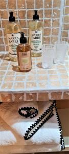 ein Regal mit drei Flaschen Seife und Handtüchern in der Unterkunft Villa Aigarden maison d'hôtes in Avignon