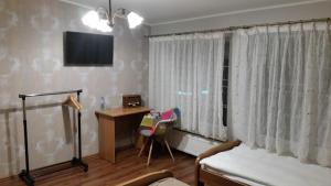 - une chambre avec un lit, un bureau et une télévision dans l'établissement Villa Lena, à Gdańsk