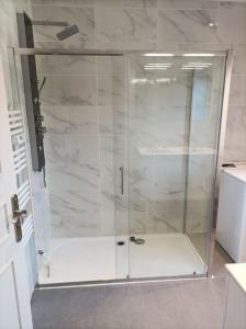 een douche met een glazen deur in de badkamer bij Gite de la Croix de la Passion in Vailly-sur-Sauldre