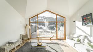 sala de estar con sofá blanco y ventana grande en KOKONO Luxury Ski Chalet Andorra, El Tarter en El Tarter