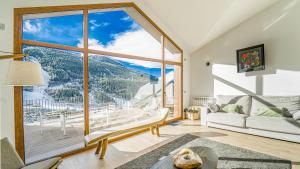 sala de estar con ventana grande con vistas a la montaña en KOKONO Luxury Ski Chalet Andorra, El Tarter en El Tarter