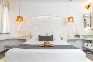 a white bedroom with a bed with a hat on it at Blue Heart Luxury Suites in Naxos Chora