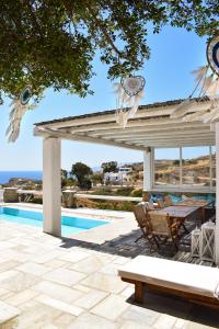 a pavilion with a table and chairs next to a pool at Villa Giulia, seaview villa in Ios Chora