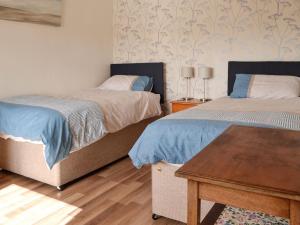 a bedroom with two beds and a wooden table at The Old Cow Shed in Wickwar