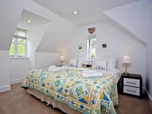 a white bedroom with a bed with a colorful bedspread at 9 The Whitehouse in Mawgan Porth