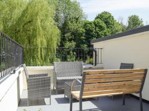 a patio with a wooden bench and chairs on a balcony at Elizabeth House in Chirk