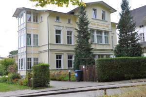 ein gelbes und weißes Gebäude mit Bäumen davor in der Unterkunft Bansin, Villa an der Waldstraße in Bansin