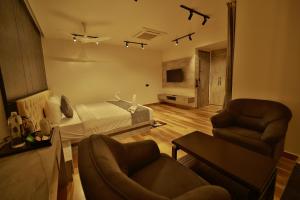 a living room with a bed and a couch and chairs at The Mysore Grand in Mysore