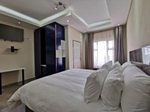 um quarto com uma cama grande e almofadas brancas em KwaNomzi Botique Lodge em Lusikisiki