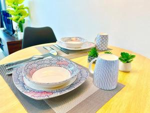 a table with plates and cups on a wooden table at H 1-5 pax Cozy house 3 Bed Trefoil Setia Alam Wifi and TV SCCC in Shah Alam