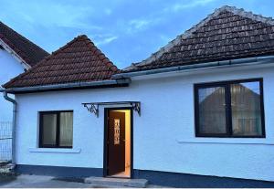 a small white house with a brown door at CASA 9 in Ferihaza