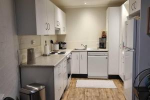 uma cozinha com armários brancos e um frigorífico branco em Guest Suite in Duffy em Weston Creek