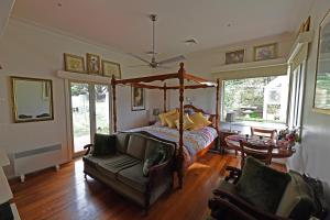 1 dormitorio con cama con dosel y sofá en Galahad's Animal Sanctuary B&B, en Gisborne