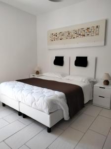 a white bedroom with a large bed and a white tile floor at Casale Mammarella in LʼAquila