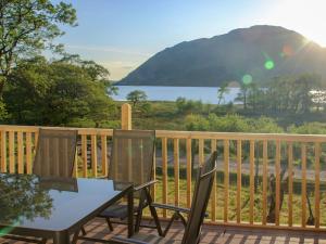 a table and chairs on a deck with a view of the water at Invernoe Cottage in Taynuilt