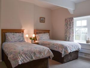 a bedroom with two beds and a window at Browney Cottage in Broadwood