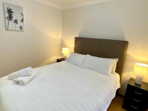 a bedroom with a large white bed with two lamps at Forrest Holiday Unit Bunbury in Glen Iris