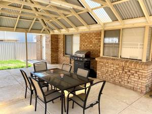 a patio with a table and chairs and a grill at Forrest Holiday Unit Bunbury in Glen Iris