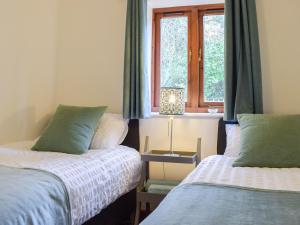 a bedroom with two beds and a window at Primrose Cottage in Ironbridge