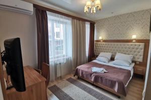 Schlafzimmer mit einem Bett und einem Flachbild-TV in der Unterkunft Вілла Калина in Truskawez