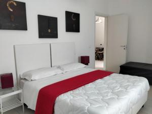 1 dormitorio con 1 cama blanca grande con manta roja en Casale Mammarella, en LʼAquila