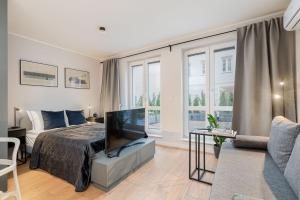 Un dormitorio con una cama, un televisor y un sofá. en Czarnowiejska 21A by Homeprime, en Cracovia