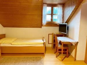 a bedroom with a bed and a desk with a computer at Pension Wiesengrund in Neuschönau