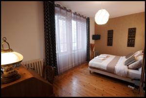 ein Schlafzimmer mit einem Bett und einer Lampe auf einem Tisch in der Unterkunft LOGIS HOTEL BELLEVUE RESTAURANT LA POMME d'OR in Coucy-le-Château-Auffrique