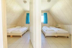 Cette chambre mansardée comprend 2 lits et des rideaux bleus. dans l'établissement Seinpaal, à Callantsoog