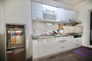 uma cozinha com armários brancos e um frigorífico de aço inoxidável em 好窩旅店 em Hengchun Old Town