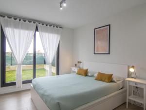 Dormitorio blanco con cama y ventana grande en Apartamento Holidea Playa San Juan de la Canal, en Santa Cruz de Bezana