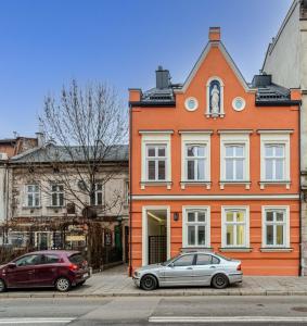 クラクフにあるCzarnowiejska 21A by Homeprimeのオレンジ色の建物の前に停車した車2台