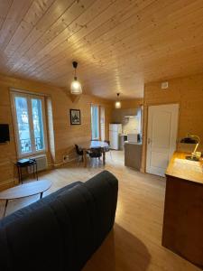 a large living room with a couch and a kitchen at Appt lumineux centre ville du Mont Dore Vue Sancy in Le Mont-Dore