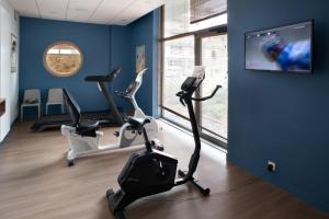 a gym with two exercise bikes and a flat screen tv at Domitys - Les Aiglons Blancs in Briançon