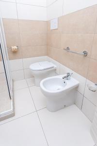 a white bathroom with a toilet and a sink at Sibari Residence in Marina di Sibari